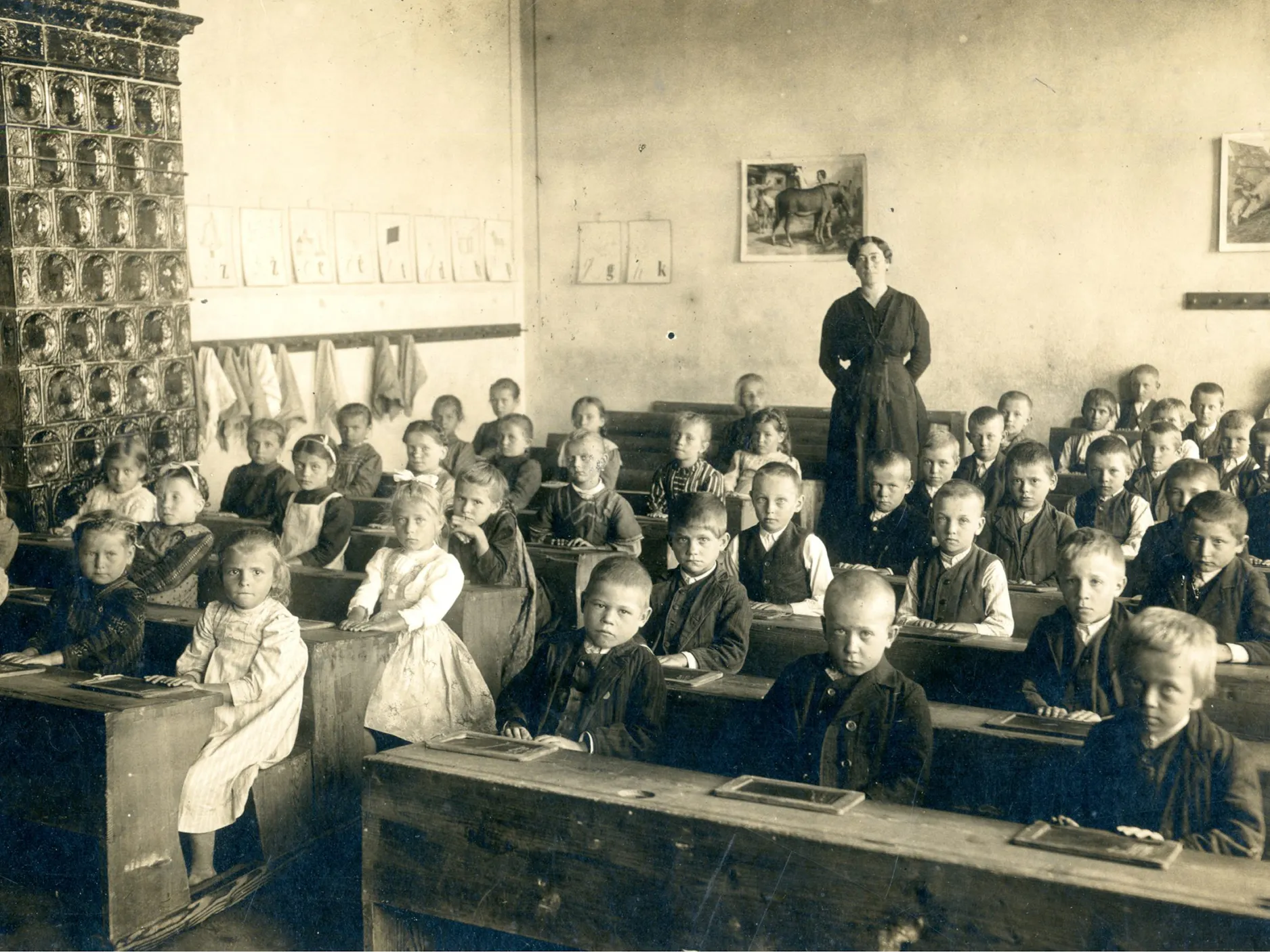 Stara sepijasta fotografija učencev in učiteljice v razredu